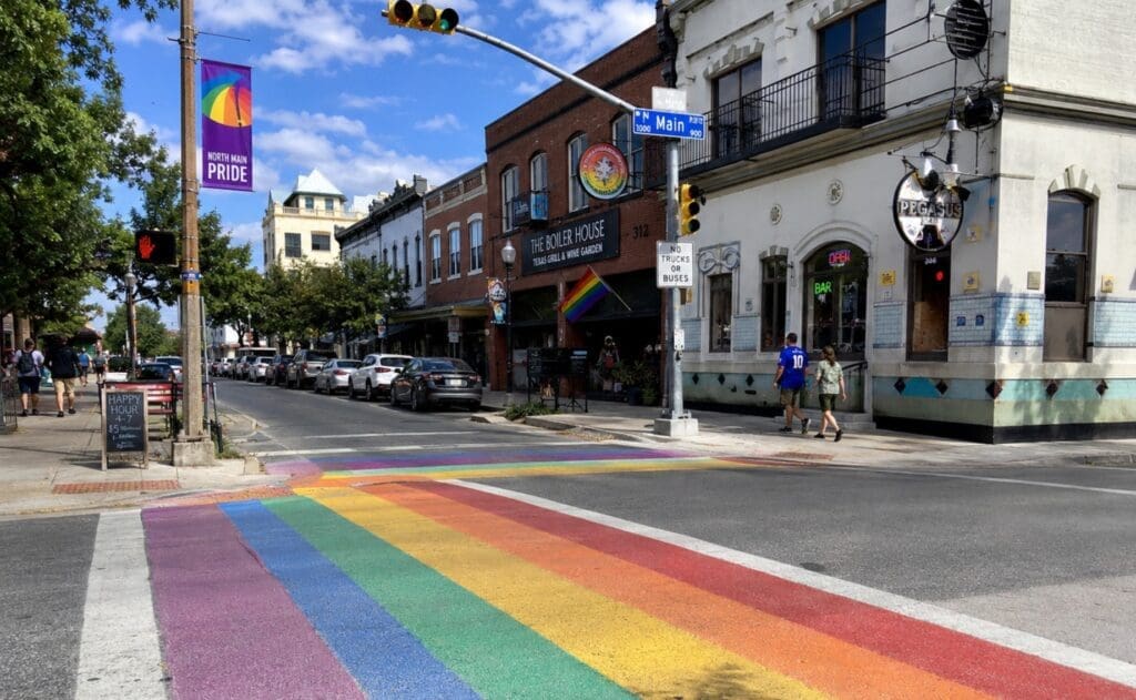 street photo of North Main Avenue in Tobin Hill showing rainbow crosswalks, Pride district signage, and venue fronts