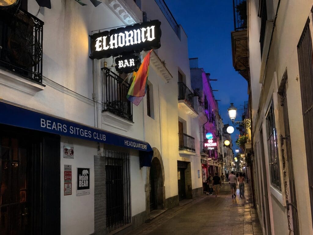 Carrer Joan Tarrida au début de la nuit, avec enseignes lumineuses et silhouettes de passants