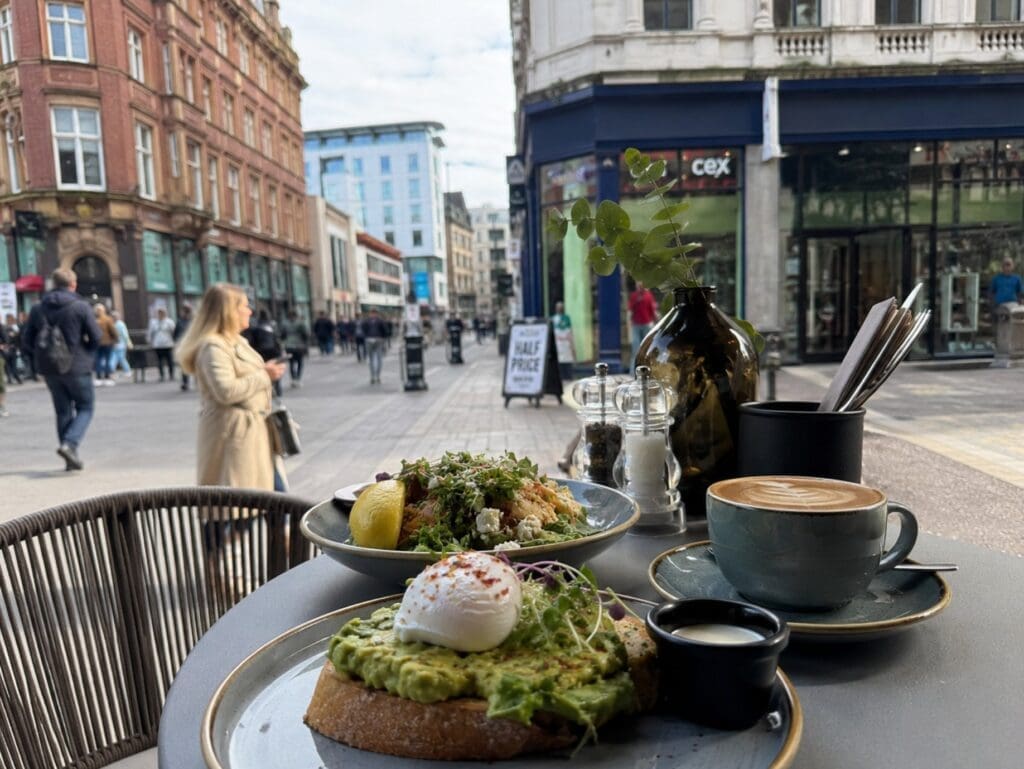 a photograph of a Leeds café table with coffee, brunch and a city-centre street scene