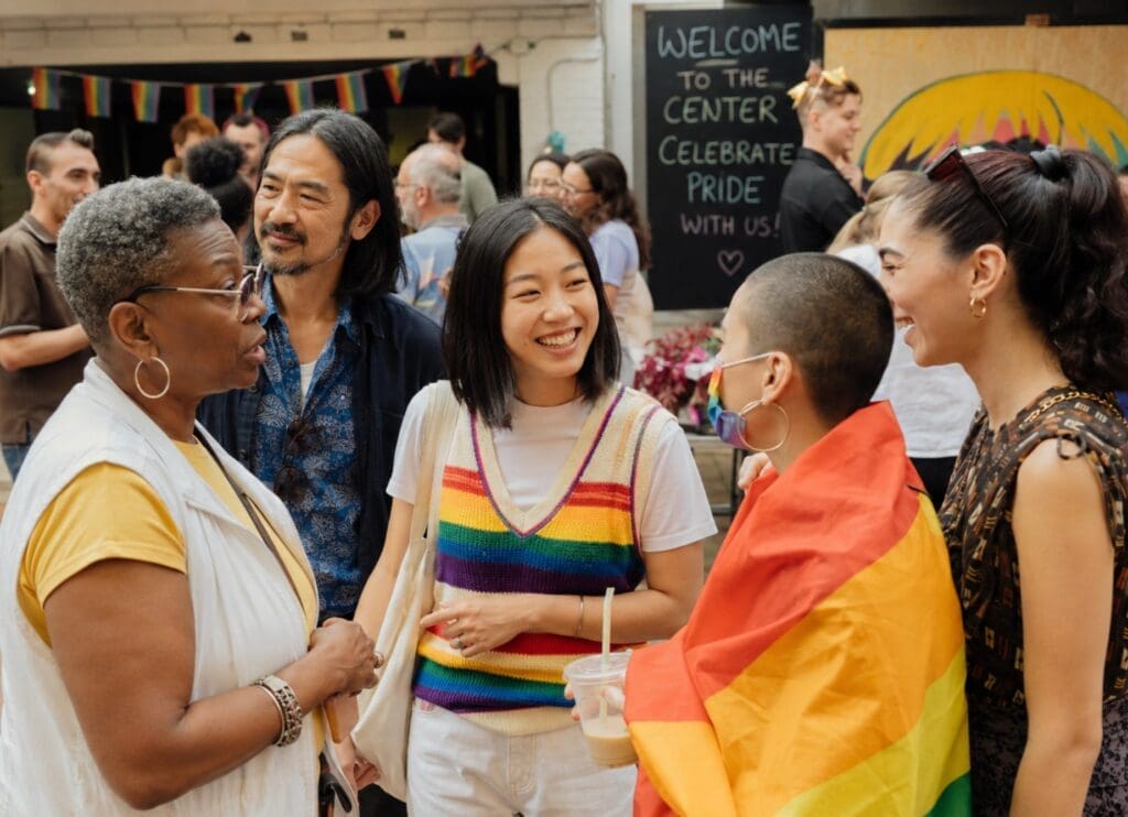 an authentic photograph of LGBTQ+ people of different ages and backgrounds participating in a community celebration
