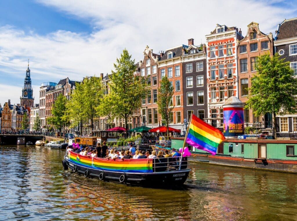bateau décoré de drapeaux arc-en-ciel sur un canal d’Amsterdam
