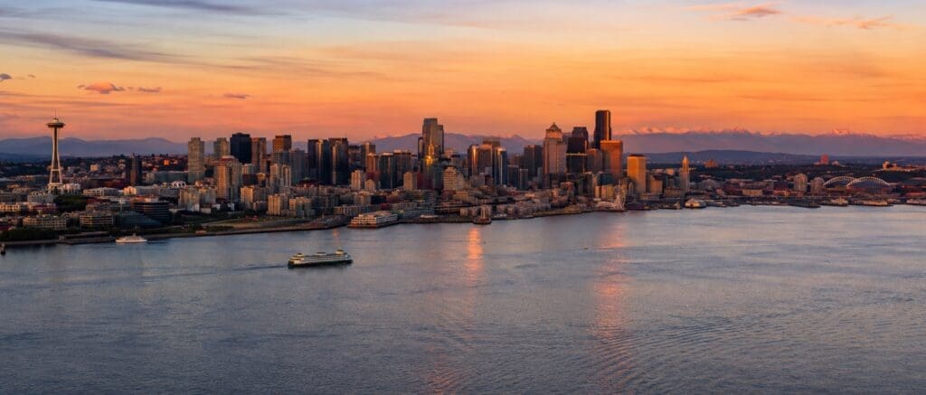 panoramic photograph of Seattle’s skyline, Elliott Bay, and the Olympic Mountains at sunset