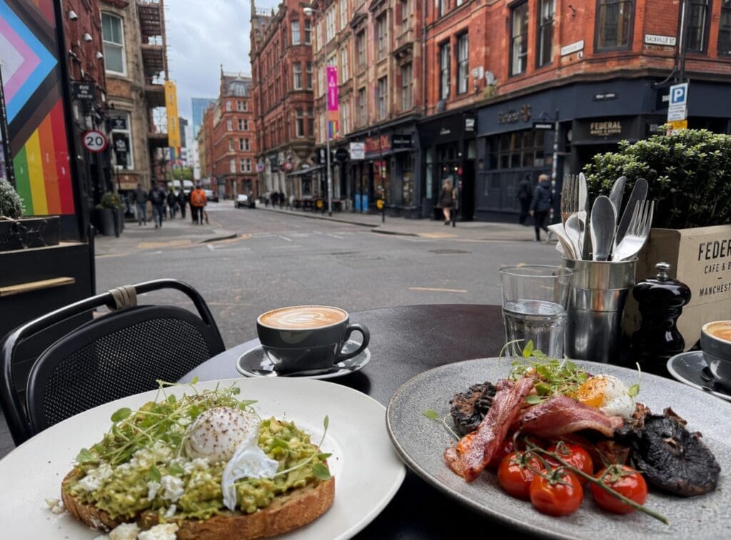 photograph of a café table near the Village: coffee, brunch, and Manchester street scene
