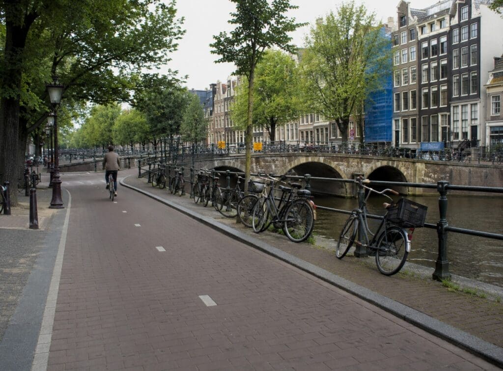 piste cyclable amstellodamoise avec vélos stationnés, canal et pont en arrière-plan