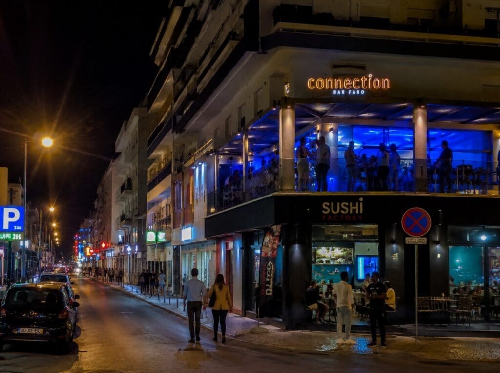 uma fotografia da Avenida Sá Carneiro à noite, com o terraço do Connection Bar visível no piso superior