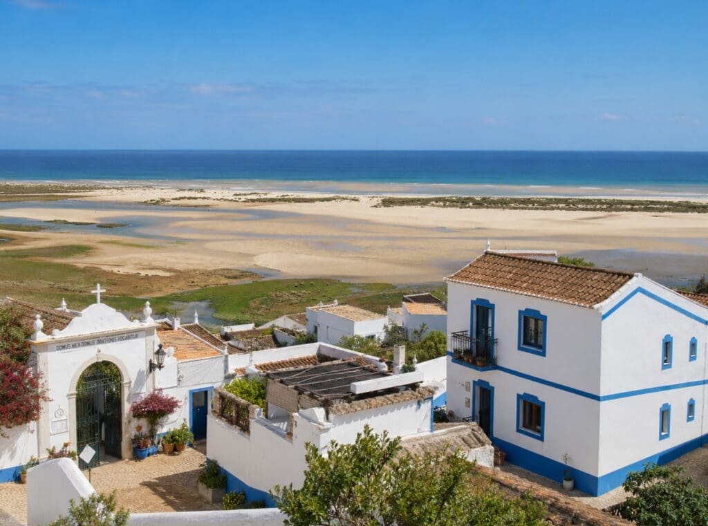uma fotografia de Cacela Velha sobre a Ria Formosa, com casas brancas e bancos de areia