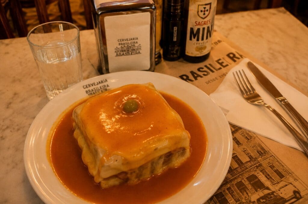 uma mesa com francesinha, copo de água, talheres e ambiente acolhedor de cervejaria portuenseO aquecimento: quando as Galerias começam a ganhar corpo
