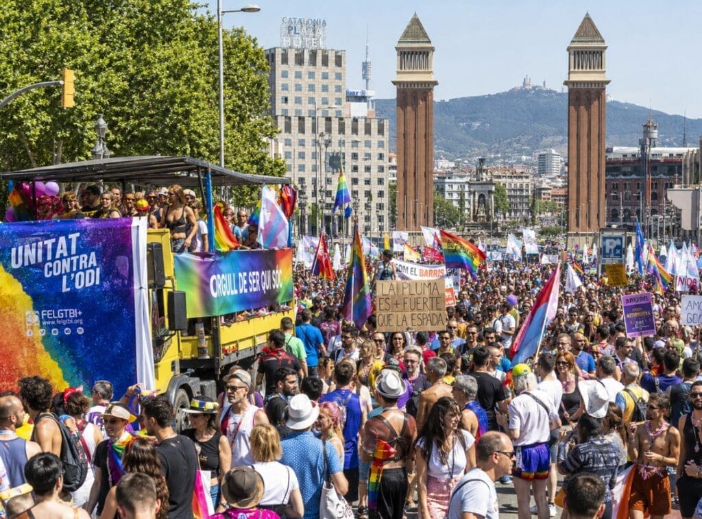 una fotografía de alta calidad de la manifestación de Pride Barcelona con pancartas, carrozas y público diverso