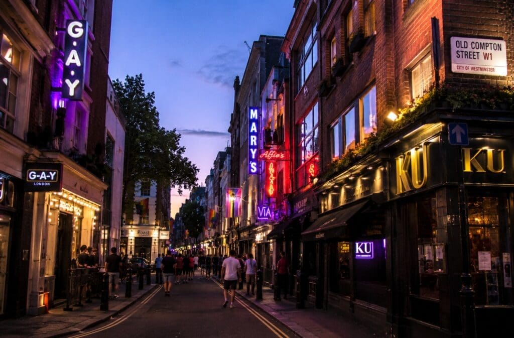 une photographie d’Old Compton Street en début de soirée, avec enseignes lumineuses