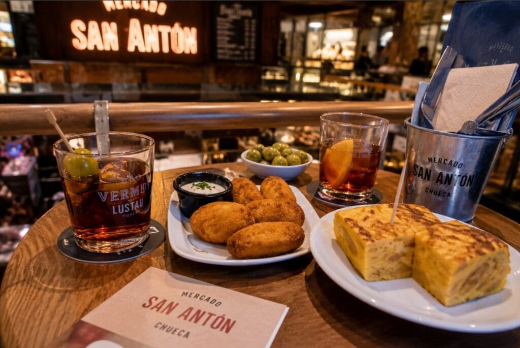 une photographie d’une table de tapas dans le Mercado de San Antón, avec croquetas, tortilla et vermouth