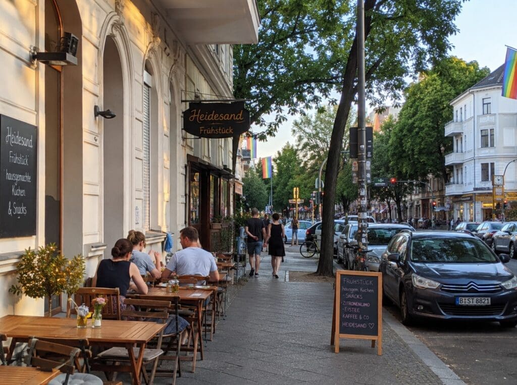 une terrasse de Schöneberg en fin d’après-midi, avec ambiance de quartier et drapeaux arc-en-ciel visibles au loin